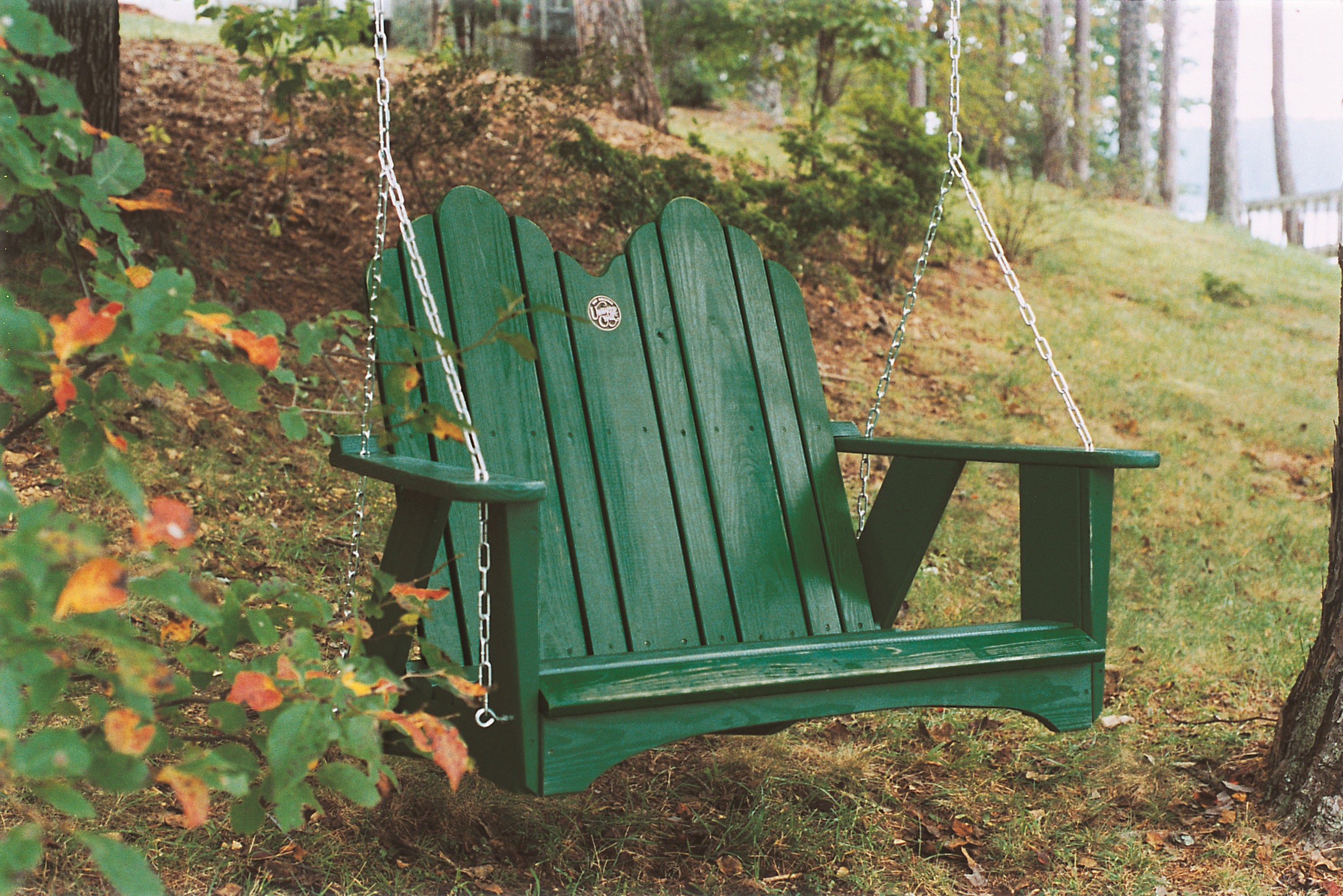 Green Adirondack porch swing with wide armrests for relaxing outdoor garden seating